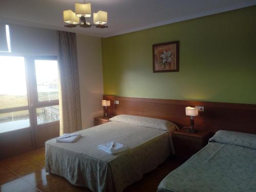 a hotel room with two beds and a window at Pensión Sol e Mar in O Pindo