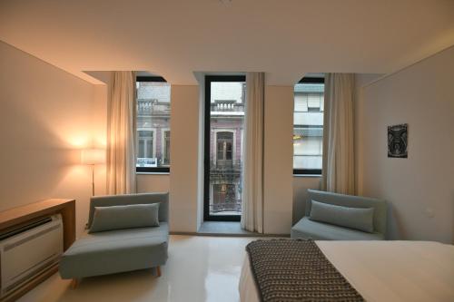 1 dormitorio con 2 sillas, 1 cama y ventanas en I Loft Porto en Oporto
