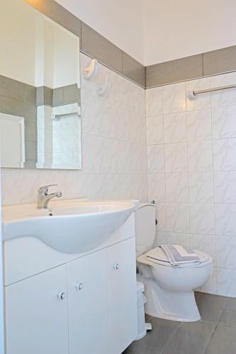 a white bathroom with a sink and a toilet at Nicos Studios & Apartments in Logaras