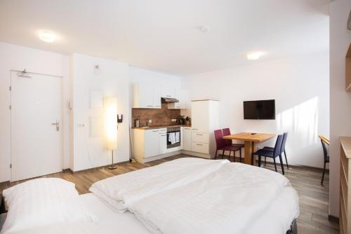 a bedroom with a white bed and a table with chairs at Apartments Leipziger Hof in Innsbruck