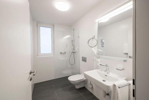 a white bathroom with a toilet and a sink at Apartments Leipziger Hof in Innsbruck