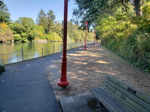a red pole next to a bench next to a river at Robin Hood Inn and Suites in Victoria