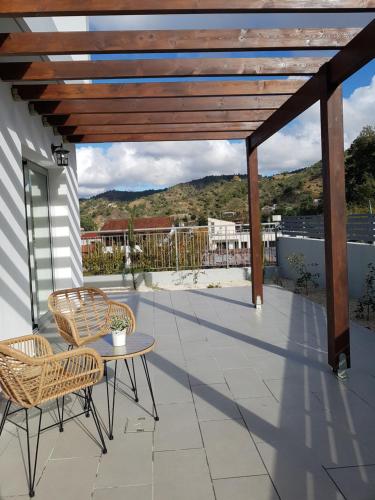 a patio with two chairs and a table and a wooden pergola at Evmelia Kakopetria Suites in Kakopetria