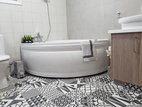 a bathroom with a white tub and a black and white tile floor at Evmelia Kakopetria Suites in Kakopetria