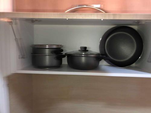 three pots and pans on a shelf in a kitchen at Appartement S+1 Jardin De Carthage in Tunis