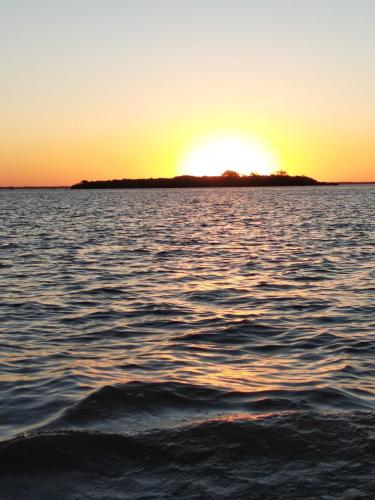 an island in the middle of a body of water at sunset at Carmelo RIVERSIDE Bungalows in Carmelo