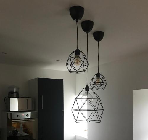 a kitchen with three lights hanging from the ceiling at Gite 5 pers avec 2h espace bien-être privatisé inclus dans le prix de la nuit 80m2 de détente in Équilly