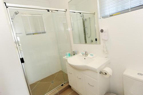 a white bathroom with a sink and a shower at Gladstone Heights Executive Apartments in Gladstone