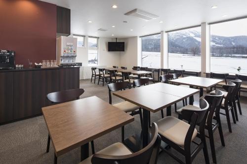 a restaurant with tables and chairs and a counter at Pensione UNO in Niseko