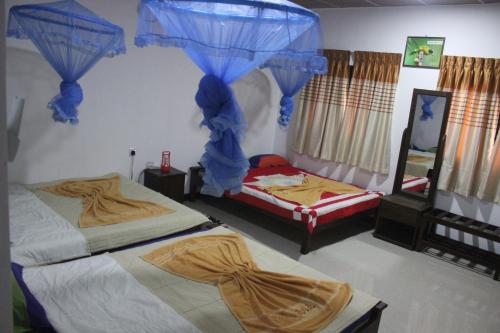 two beds in a room with blue drapes at Wilpattu Holiday Home in Nochchiyagama