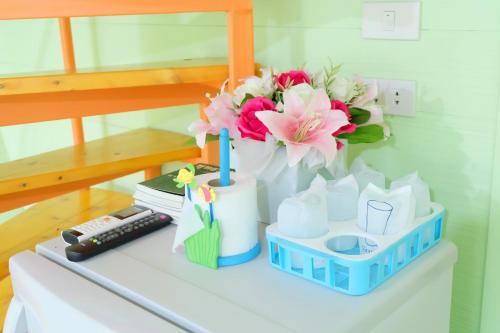 a table with a vase of flowers and a remote control at A Houses Homestay in Nakhon Ratchasima