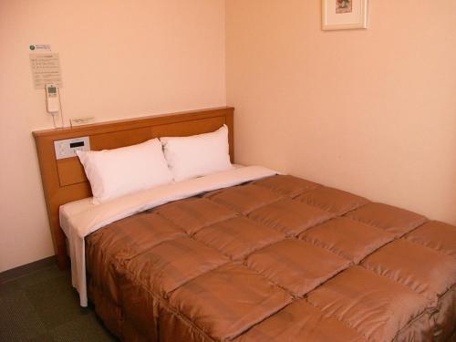 a small bedroom with a bed in a room at Hotel Route-Inn Aso Kumamoto Airport Ekimae in Ozu