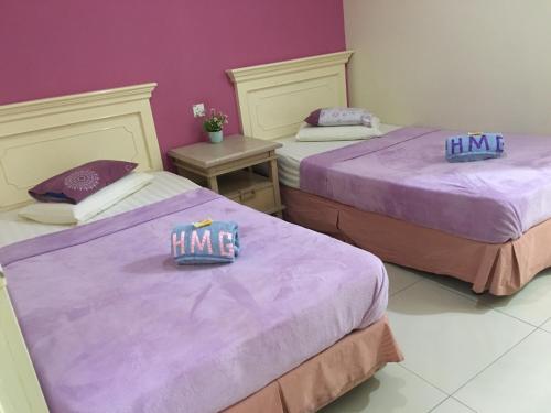 two beds in a room with purple sheets at Hotel Morning Glory in Kudat