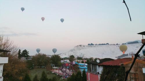 a group of hot air balloons flying over a town at Mustafa Hotel in Pamukkale