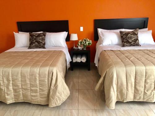 2 camas en una habitación con pared de color naranja en ZAMORA EJECUTIVO EXPRESS, en Zamora de Hidalgo