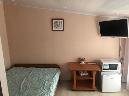 バイカリスクにあるBerezovy Guest Houseのベッド、小さなテーブル、テレビが備わる客室です。
