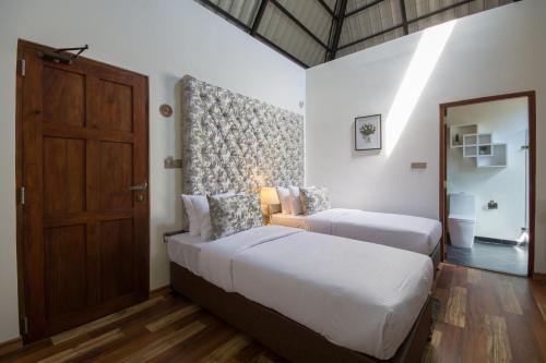 a bedroom with two beds and a wooden door at The Wind Castle in Nuwara Eliya