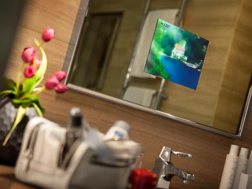 a bathroom sink with a mirror and a tv on the wall at Hotel Cavour in Milan