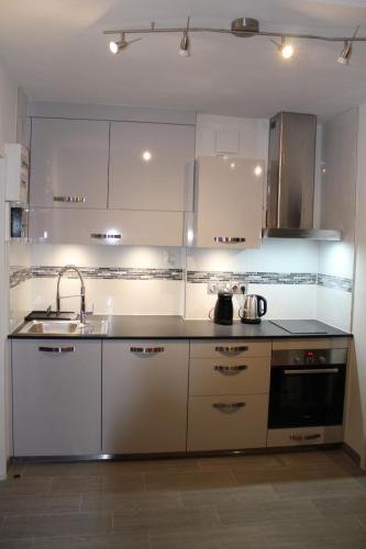 une cuisine avec des armoires blanches et un évier dans l'établissement Grand Studio rénové, tout confort, belles prestations - Résidence du Bois de l'Ours, aux Rousses