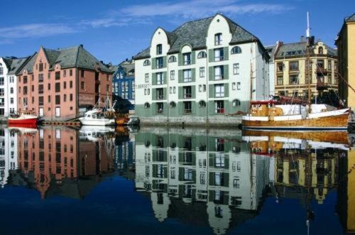 a group of buildings with their reflections in the water at Hotel Brosundet in Ålesund