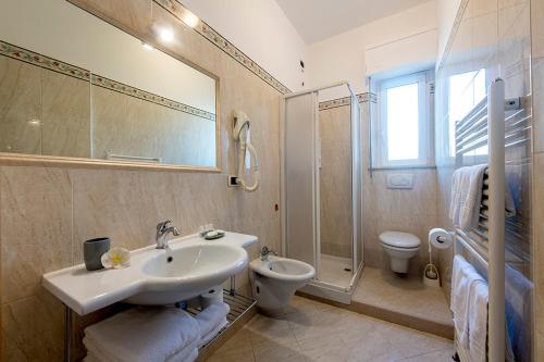 a bathroom with a sink and a toilet and a mirror at Hotel Le Soleil in San Benedetto del Tronto