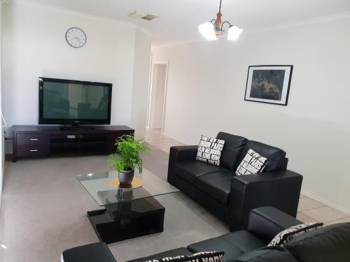 Una sala de estar con un sofá negro y un televisor. en SAN Mateo, en Mildura