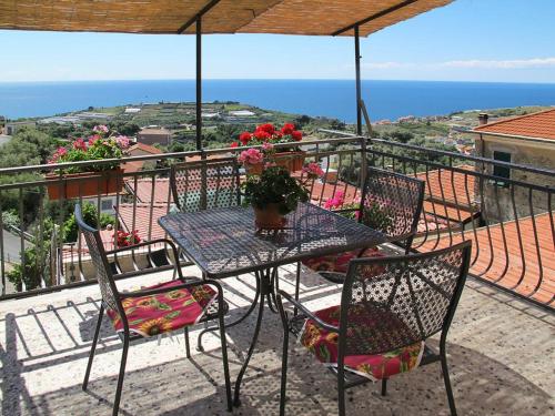 einen Tisch und Stühle auf einem Balkon mit Meerblick in der Unterkunft Agriturismo Il Vecchio Mulino in Terzorio