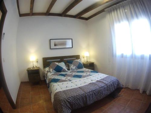 a bedroom with a bed and two lamps and a window at Apartamento los arcos in Cobisa