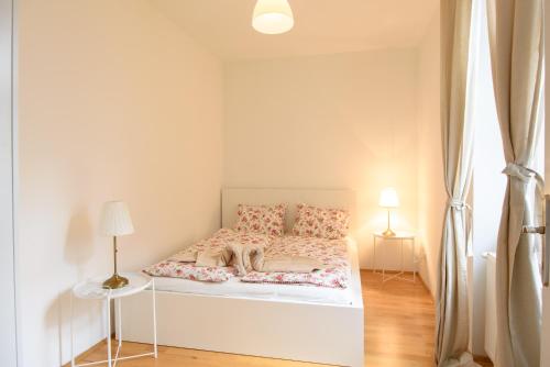 biała sypialnia z łóżkiem z kwiatami w obiekcie Central Living Apartment 1090 Vienna w Wiedniu