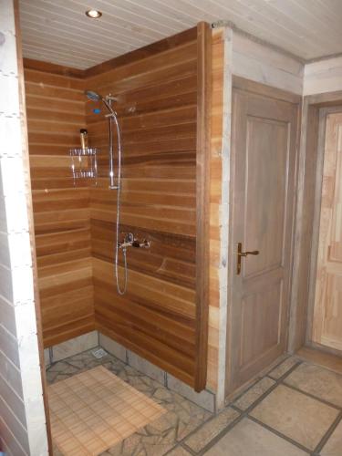 a shower in a room with a wooden wall at Holiday House & Sauna in Druskininkai in Neravai