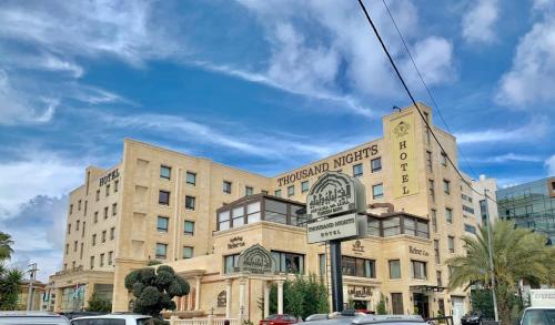 a large building with a sign in front of it at Thousand Nights Hotel Amman - فندق ثاوزند نايتس عمان in Amman