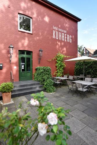 ein rotes Gebäude mit einer grünen Tür sowie Tischen und Stühlen in der Unterkunft Hotel KUHBERG Hamburg in Hamburg