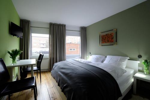 a bedroom with a bed and a desk and a window at Hotel KUHBERG Hamburg in Hamburg