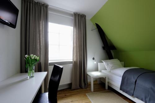 a bedroom with a bed and a desk and a window at Hotel KUHBERG Hamburg in Hamburg