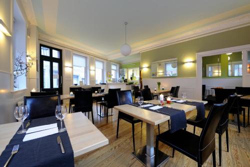 um restaurante com mesas e cadeiras num quarto em Hotel KUHBERG Hamburg em Hamburgo