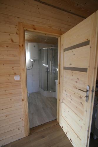 Eine Holztür führt in ein Bad mit einer Dusche. in der Unterkunft Eko Przystanek in Kępie Żaleszańskie