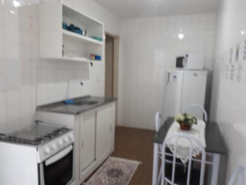 una piccola cucina con piano cottura e frigorifero di Quartos Em Casa Caxias - Pousada Paraíso a Duque de Caxias