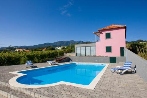 a swimming pool with two chairs and a house at A Casa do Lagar in São Jorge