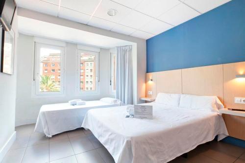 - une chambre avec 2 lits et un mur bleu dans l'établissement Putxet by gaiarooms, à Barcelone