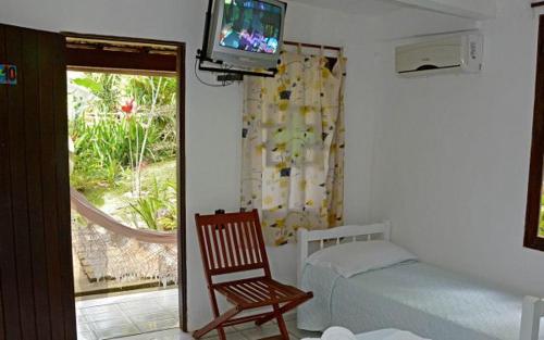 1 dormitorio con 1 cama, 1 silla y TV en Pousada 4 Ventos, en Arraial d'Ajuda