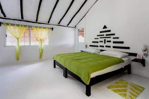 a bedroom with a green bed in a white room at Casa Alex 100m from the beach in Tulum