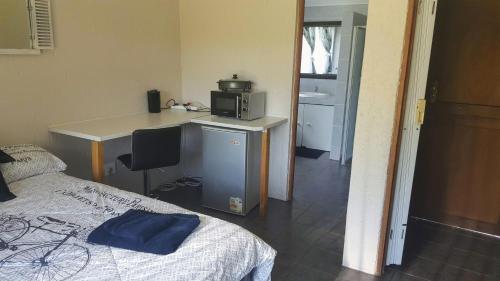 Schlafzimmer mit einem Bett und einem Schreibtisch mit einer Mikrowelle in der Unterkunft Bachelor Apartment 2 in Midrand