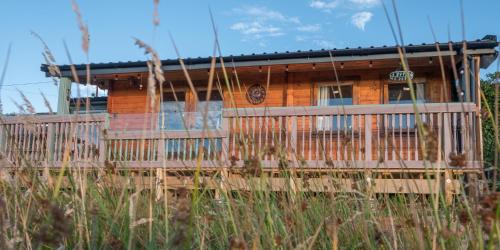 een houten huis met een hek ervoor bij Enlli Fach pet friendly Cabin , sleeps 2 adults 2 children not suitable for contract workers due to parking in Borth