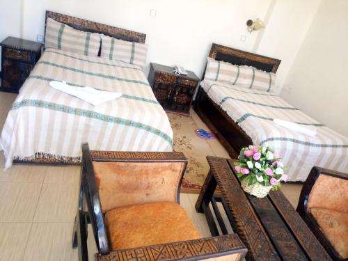 two beds in a room with chairs and a table at Honey Land Hotel Lalibela in Lalībela