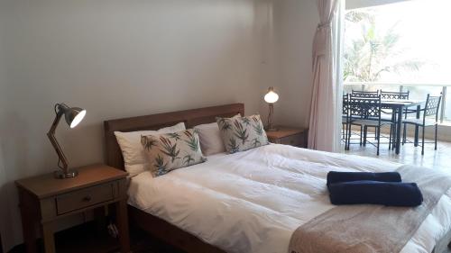 ein Bett mit blauem Kissen in einem Schlafzimmer in der Unterkunft Ballito Manor Gardens 304 in Ballito