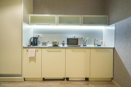 a kitchen with white cabinets and a microwave at Opera Passage Hotel & Apartments in Lviv