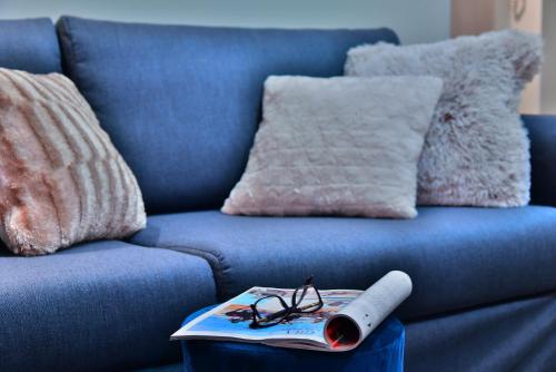 a book and glasses on a table next to a blue couch at Apartamenty Sjesta Centrum in Kudowa-Zdrój