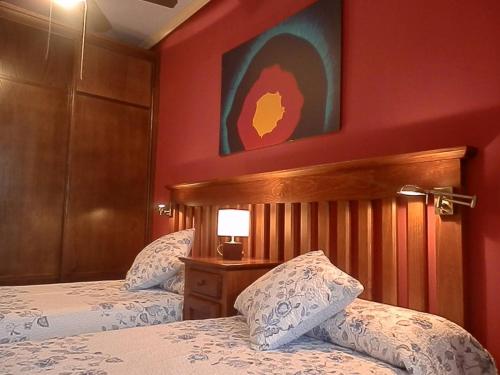 een slaapkamer met 2 bedden en een rode muur bij -2-COMO EN CASA, en centro historico de Ubeda in Úbeda