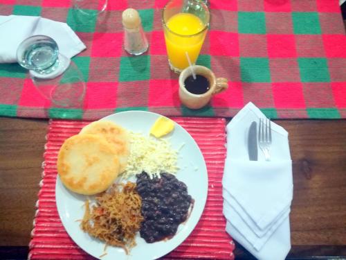 a plate of food with eggs bread and blackberries and cheese at Hotel Villa Playa Grande in Playa Grande