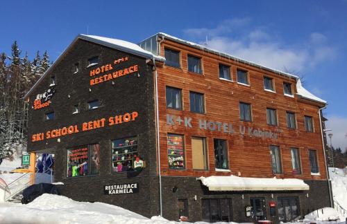 a large wooden building with a ski shop in the snow at Hotel U Kabinky in Janske Lazne